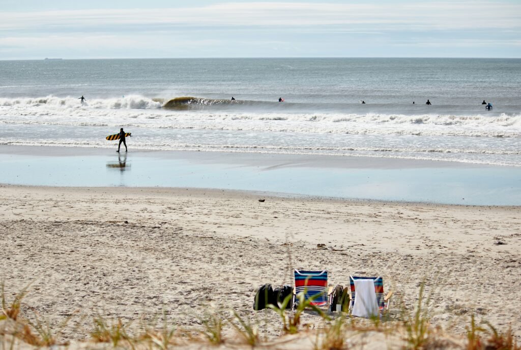 Surfer walking on Rockaway Beach, Queens, NY, USA. Photo by Hayley Pfizer