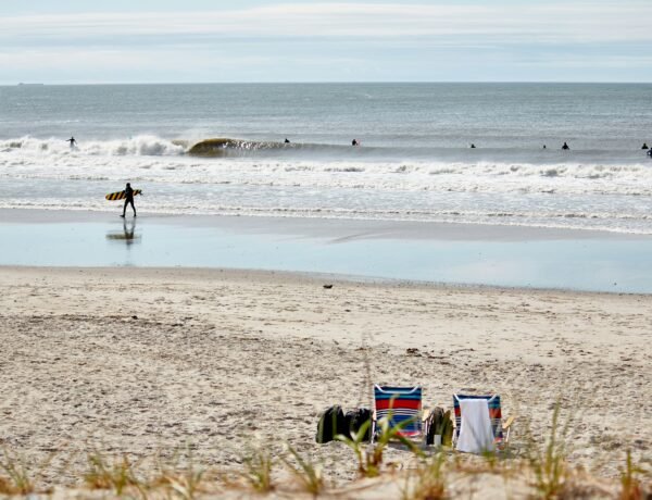 Surfer walking on Rockaway Beach, Queens, NY, USA. Photo by Hayley Pfizer