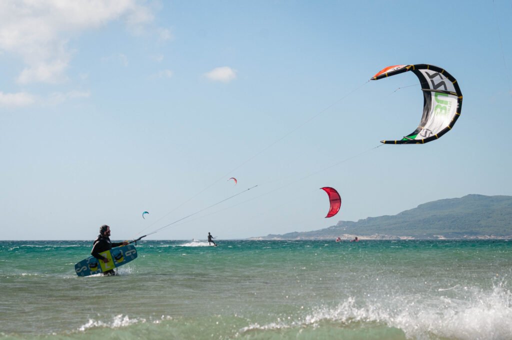 Kitesurfer in Tarifa with Kite in air and kiteboard in hand
