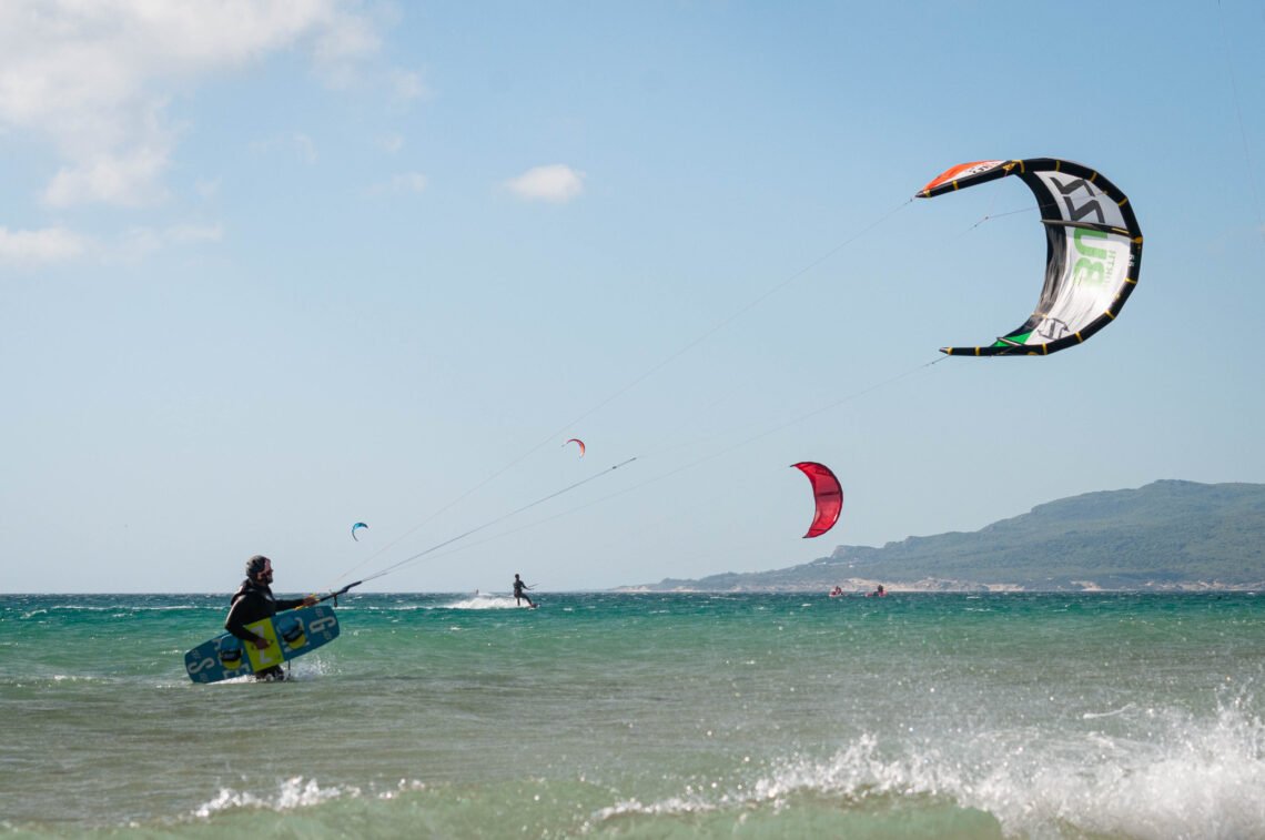 Kitesurfer in Tarifa with Kite in air and kiteboard in hand