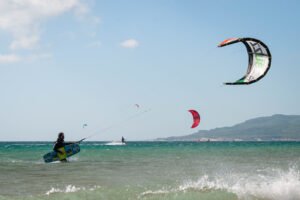 Kitesurfer in Tarifa with Kite in air and kiteboard in hand